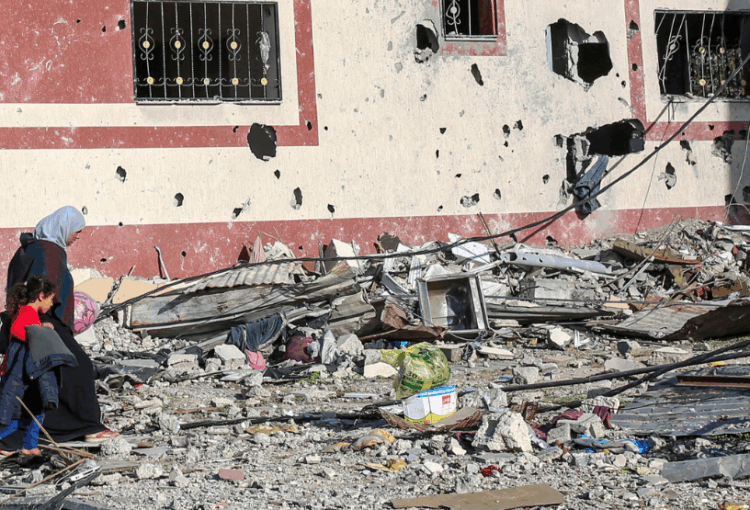 Mother and daughter walk through rubble in Gaza.